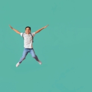 Jumping little schoolboy on color background